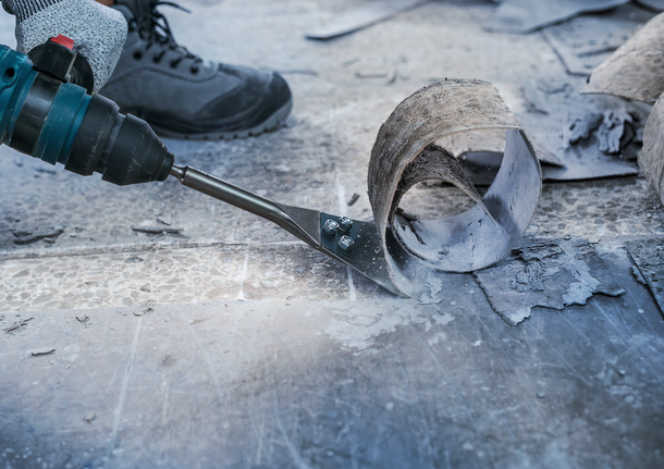 บุคคลที่สวมอุปกรณ์ด้านความปลอดภัยใช้เครื่องมือไฟฟ้าในการถอดวัสดุพื้นออก