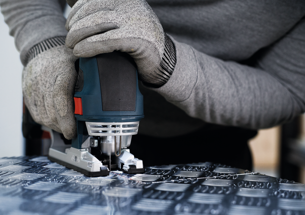 ผู้ที่สวมอุปกรณ์ความปลอดภัยใช้จิ๊กซอว์ตัดโลหะที่มีลวดลาย