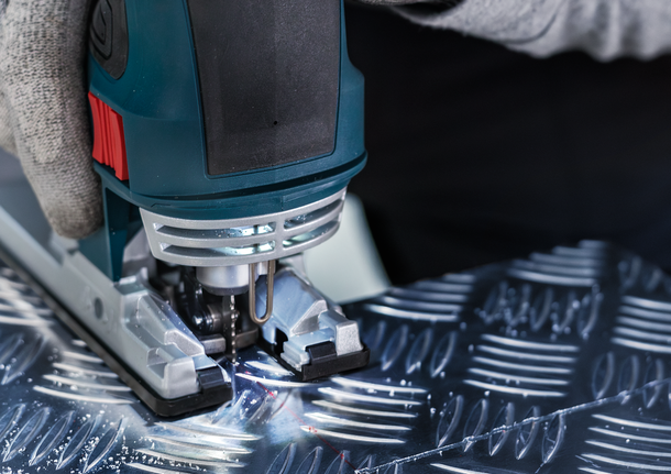 บุคคลที่สวมอุปกรณ์ความปลอดภัยใช้จิ๊กซอว์ตัดโลหะที่มีลวดลาย