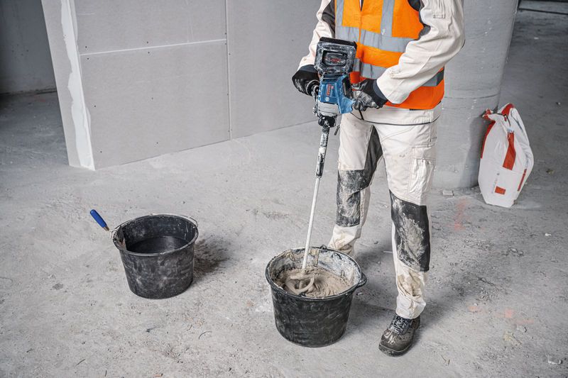 บุคคลที่สวมอุปกรณ์ป้องกันความปลอดภัยผสมวัสดุก่อสร้างโดยใช้กลไกการกวน.