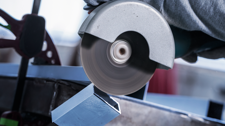 คนงานสวมอุปกรณ์ความปลอดภัยใช้เลื่อยวงเดือนตัดคานโลหะ.