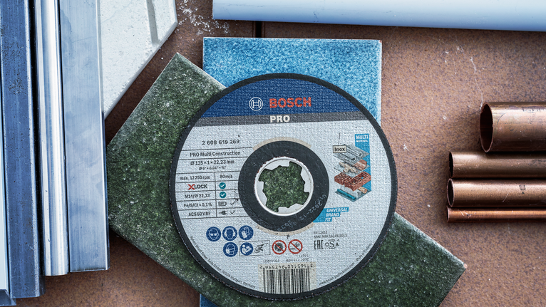 ใบตัดวางอยู่บนกระเบื้องสี ล้อมรอบด้วยท่อโลหะและพลาสติก