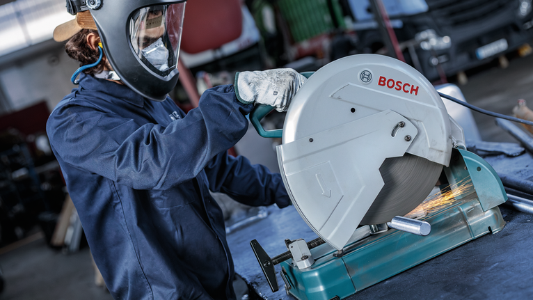 บุคคลที่สวมอุปกรณ์ความปลอดภัยกำลังตัดท่อโลหะด้วยเลื่อยวงเดือน