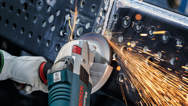 บุคคลที่สวมอุปกรณ์ความปลอดภัยบดคานโลหะทำให้เกิดประกายไฟ