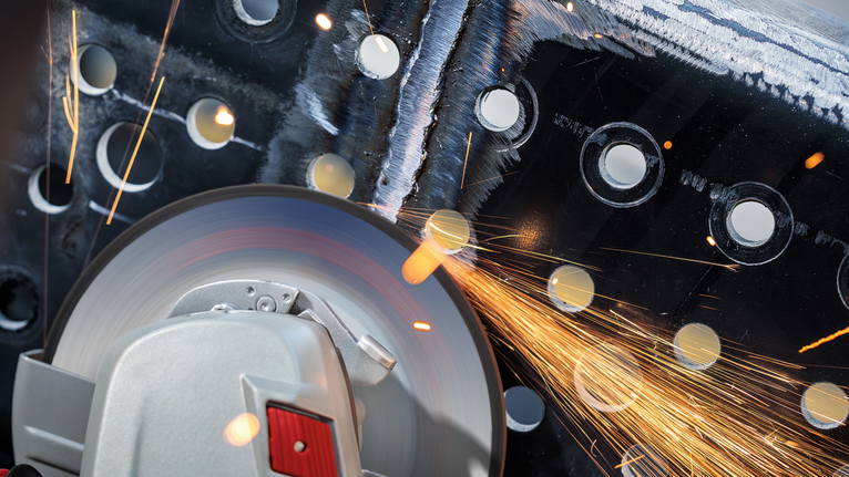 เครื่องมือตัดกำลังบดผ่านโลหะที่มีรูพรุน มีประกายไฟกระเด็นออกมา