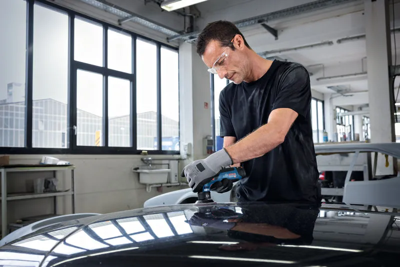 บุคคลที่สวมอุปกรณ์ความปลอดภัยกำลังขัดหลังคารถด้วยเครื่องขัดแบบสุ่มวงโคจร.