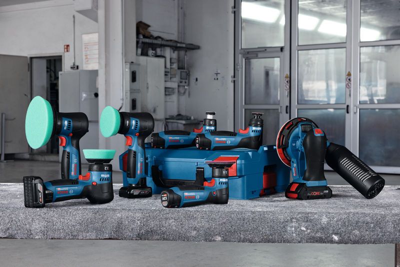 เครื่องมือขัดและขัดแบบไร้สายพร้อมกล่องเก็บสีน้ำเงินบนโต๊ะทำงานในโรงงาน.