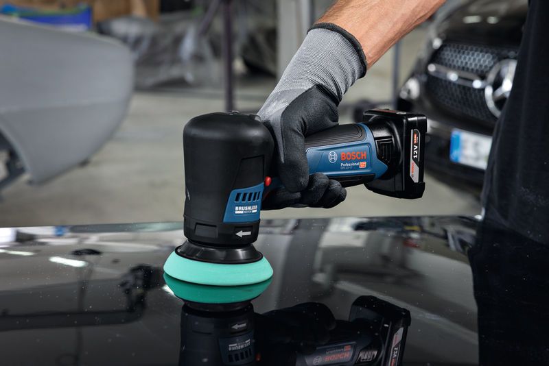 ผู้ที่สวมอุปกรณ์ด้านความปลอดภัยใช้เครื่องขัดแบบไร้สายบนผิวรถ.