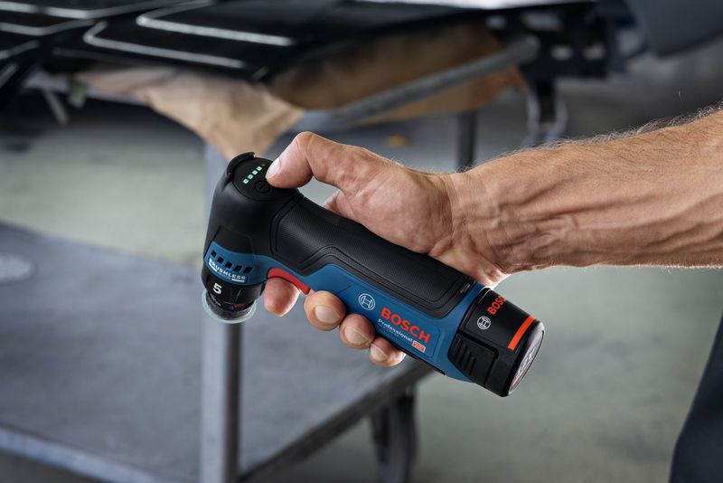 คนๆ หนึ่งถือเครื่องขัดแบบสุ่มวงโคจรแบบไร้สายในโรงงานแห่งหนึ่ง.