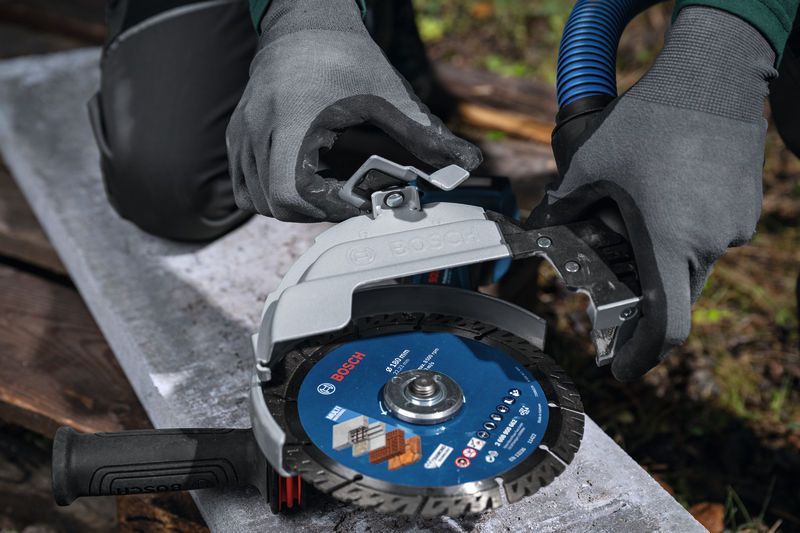 บุคคลที่สวมอุปกรณ์ด้านความปลอดภัยกำลังติดอุปกรณ์ป้องกันฝุ่นเข้ากับเครื่องเจียรขนาดใหญ่.