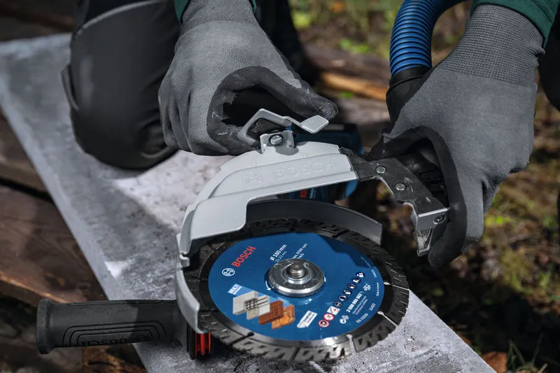 บุคคลที่สวมอุปกรณ์ด้านความปลอดภัยกำลังติดอุปกรณ์ป้องกันฝุ่นเข้ากับเครื่องเจียรขนาดใหญ่.