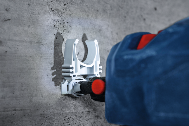 สว่านโรตารี่เจาะเข้าไปในคอนกรีตเพื่อติดตั้งตัวยึดสีขาว.