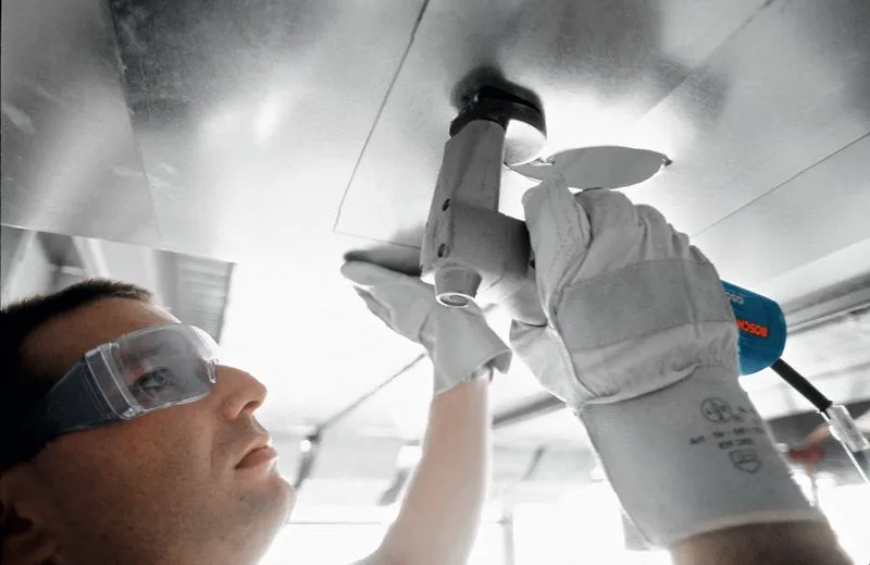 บุคคลที่สวมอุปกรณ์ความปลอดภัยใช้กรรไกรตัดแผ่นโลหะ