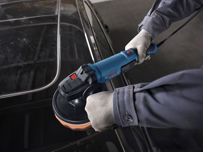 บุคคลที่สวมอุปกรณ์ความปลอดภัยกำลังขัดหลังคารถด้วยเครื่องขัดไฟฟ้า.