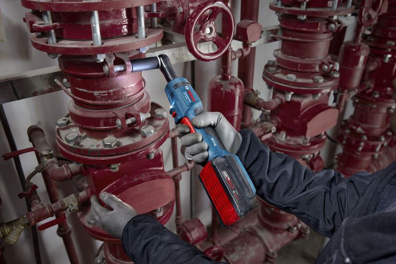 บุคคลที่สวมอุปกรณ์ด้านความปลอดภัยกำลังขันน็อตท่อด้วยประแจขันแบบไม่มีเกียร์ไร้สาย.