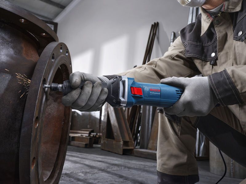 บุคคลที่สวมอุปกรณ์ด้านความปลอดภัยใช้เครื่องเจียรตรงเพื่อเจียรภายในท่อโลหะขนาดใหญ่.