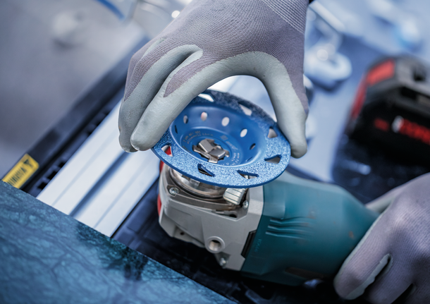 บุคคลที่สวมอุปกรณ์ด้านความปลอดภัยกำลังติดแผ่นเจียรเข้ากับเครื่องมือไฟฟ้า.