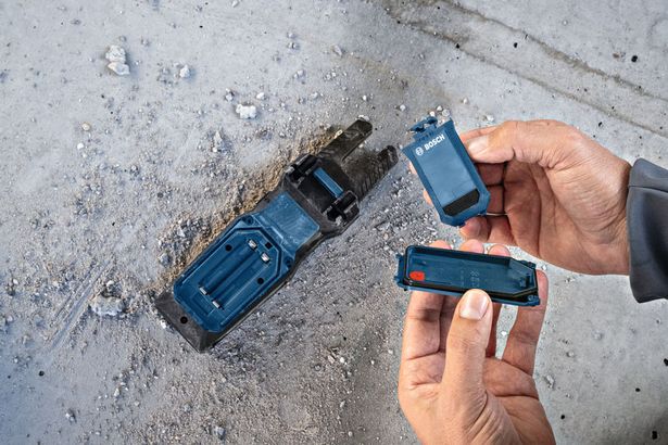 BA 3.7V 1.0Ah A คนกำลังเปลี่ยนแบตเตอรี่ในฐานเครื่องมือไฟฟ้าบนพื้นคอนกรีตที่เต็มไปด้วยฝุ่น