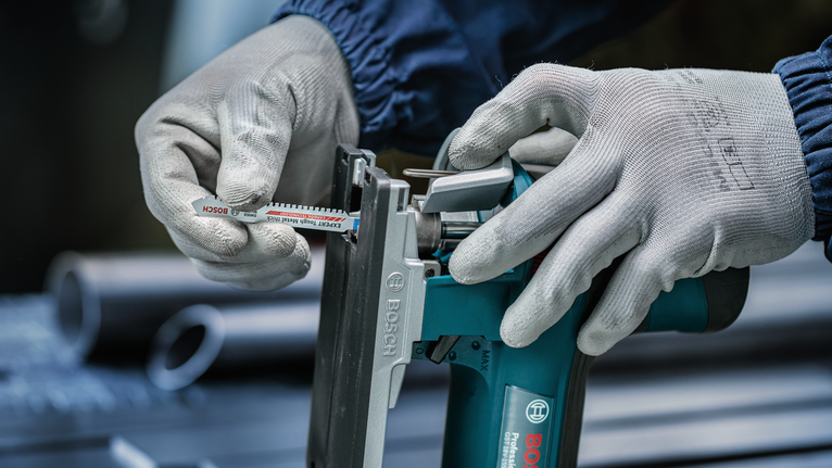 บุคคลที่สวมอุปกรณ์ด้านความปลอดภัยสอดใบเลื่อยเข้าไปในเครื่องมือไฟฟ้า