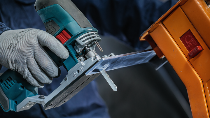 ผู้ที่สวมอุปกรณ์ความปลอดภัยใช้จิ๊กซอว์ตัดแผ่นพลาสติกใส