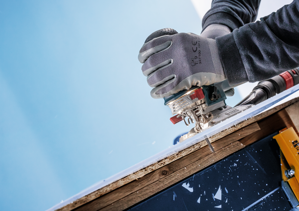 คนงานที่สวมอุปกรณ์ความปลอดภัยใช้เลื่อยจิ๊กซอว์ตัดไม้ลามิเนตชิ้นหนึ่ง.