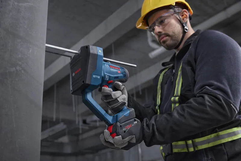 บุคคลที่สวมอุปกรณ์ป้องกันความปลอดภัยกำลังตัดแกนเกลียวด้วยเครื่องตัดแกนแบบไร้สาย.