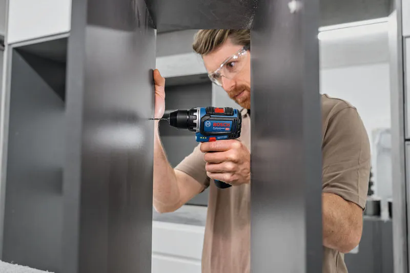 บุคคลที่สวมอุปกรณ์ความปลอดภัยกำลังเจาะเข้าไปในแผงตู้ที่มืด