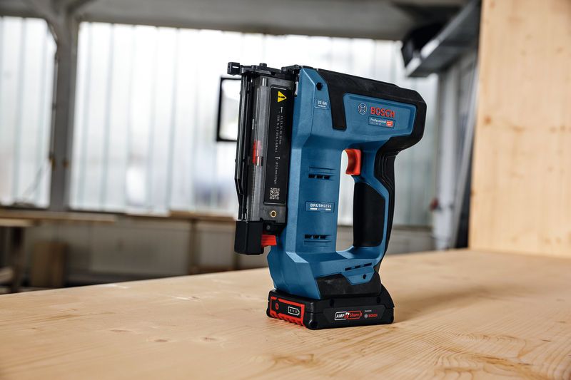 ปืนยิงตะปูไร้สายตั้งตรงบนโต๊ะไม้ในโรงงาน.