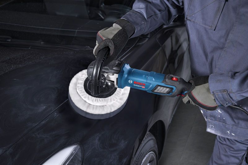 ผู้ที่สวมอุปกรณ์ด้านความปลอดภัยกำลังใช้เครื่องขัดเงาฝากระโปรงรถสีดำ.