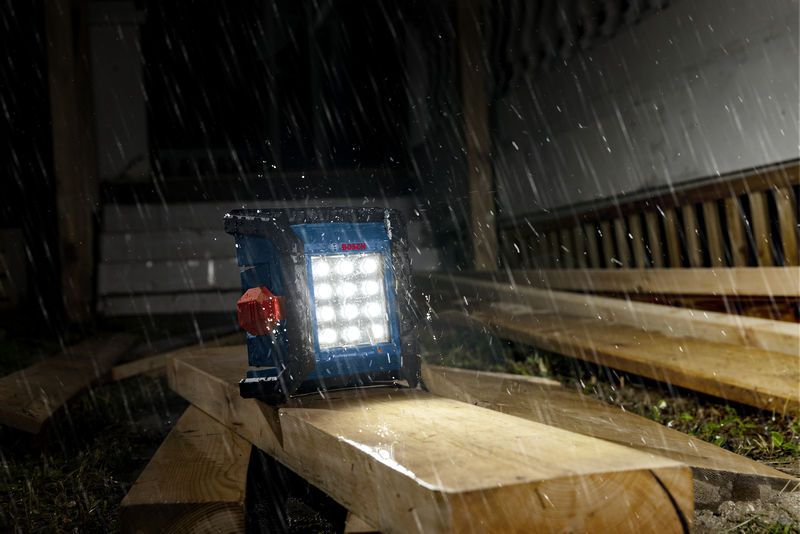 ไฟส่องสว่างหน้างานไร้สายส่องสว่างแผ่นไม้ในยามฝนตกหนักที่ไซต์ก่อสร้าง.