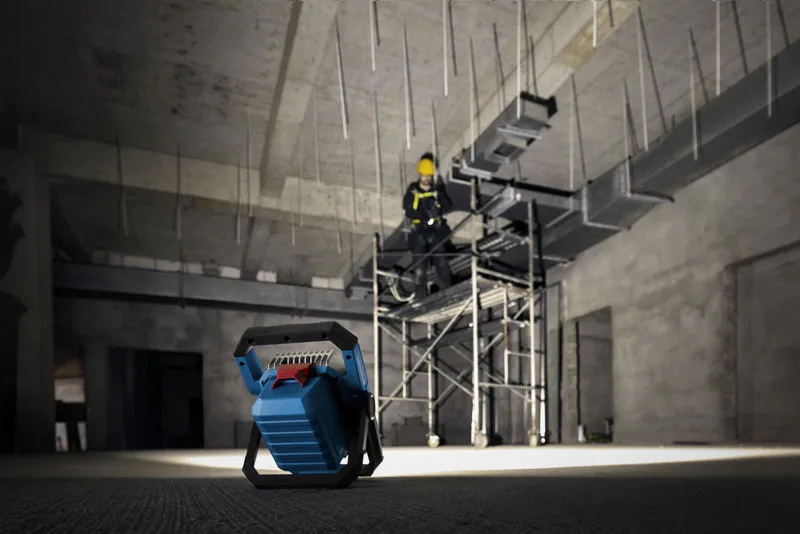 ไฟส่องสว่างหน้างานไร้สายที่ให้แสงสว่างแก่บุคคลที่สวมอุปกรณ์ด้านความปลอดภัยบนนั่งร้าน.