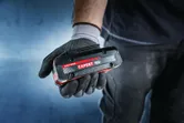 แบตเตอรี่ Bosch Expert 18V ถืออยู่ในมือที่สวมถุงมือ.