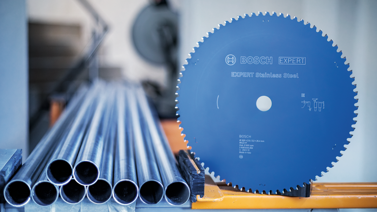 ใบเลื่อยวงเดือนข้างท่อโลหะที่เรียงซ้อนกันบนสถานีงานอุตสาหกรรม.