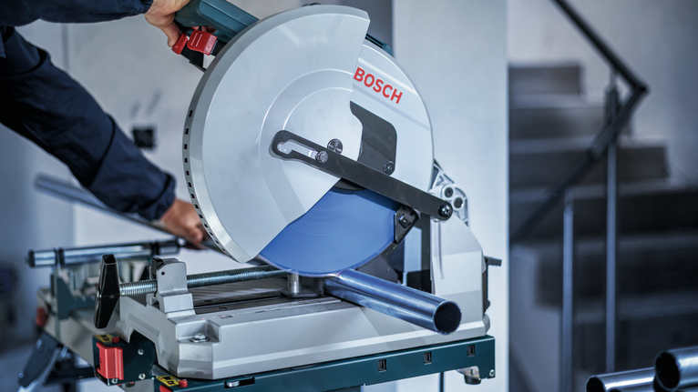 บุคคลที่สวมอุปกรณ์ความปลอดภัยกำลังตัดท่อโลหะด้วยเลื่อยวงเดือน.