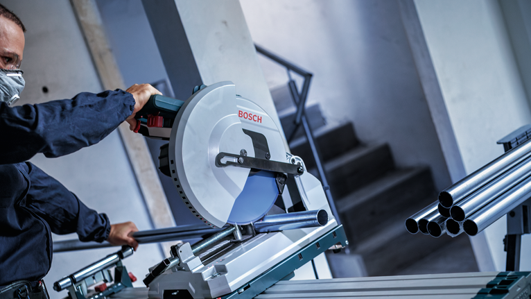 บุคคลที่สวมอุปกรณ์ความปลอดภัยกำลังตัดท่อโลหะด้วยเลื่อยวงเดือน.