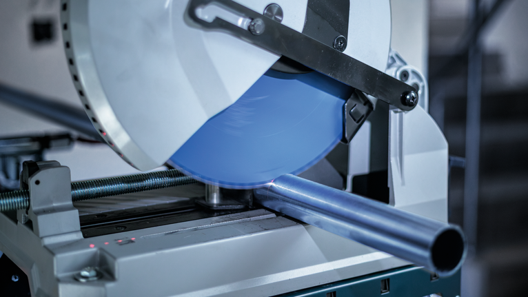 ใบเลื่อยตัดโลหะกำลังเลื่อยท่อเหล็กในโรงงาน.