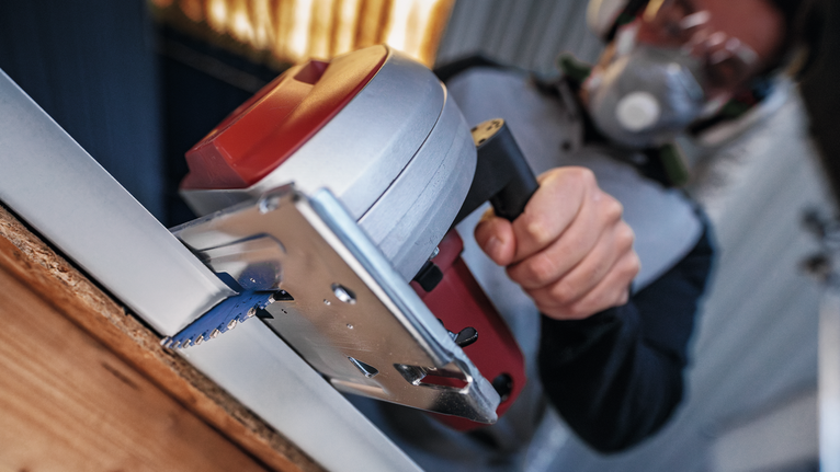 บุคคลที่สวมอุปกรณ์ความปลอดภัยกำลังตัดกระดานด้วยเลื่อยวงเดือน