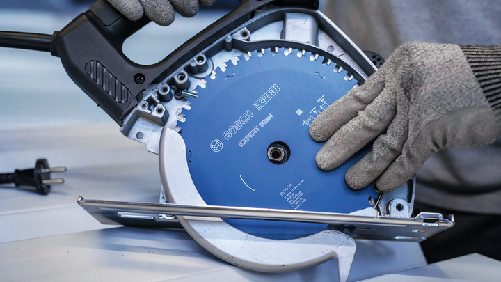 บุคคลที่สวมอุปกรณ์ด้านความปลอดภัยกำลังยึดใบเลื่อยวงเดือนไว้ในเครื่องมือไฟฟ้า