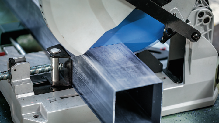 ใบเลื่อยตัดโลหะจะตัดผ่านคานเหล็กขนาดใหญ่ในโรงงานอุตสาหกรรม.