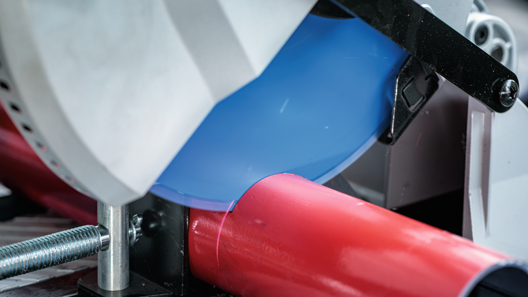 ใบเลื่อยวงเดือนตัดผ่านท่อโลหะสีแดงในโรงงานแห่งหนึ่ง.