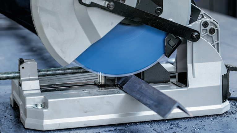 เลื่อยตัดโลหะตัดผ่านแท่งเหล็กบนโต๊ะโรงงาน.