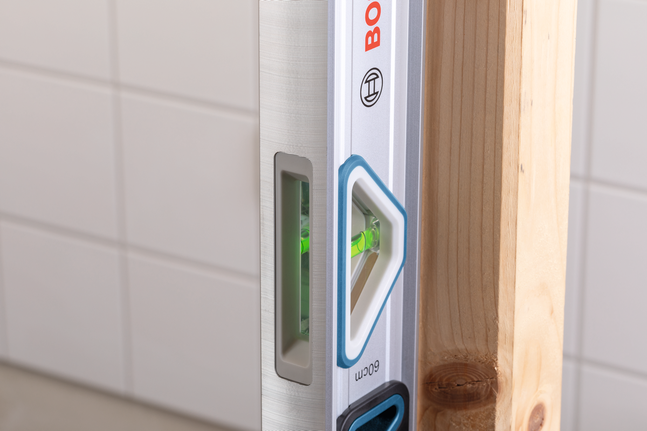 ระดับน้ำใช้ตรวจสอบความตรงในแนวดิ่งของคานไม้เทียบกับผนังกระเบื้อง