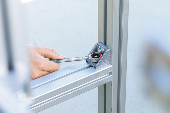 บุคคลใช้ประแจวงล้อขันน็อตบนโครงโลหะให้แน่น