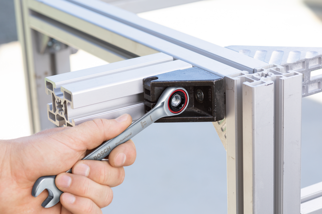 คนกำลังขันน็อตบนโครงอะลูมิเนียมด้วยประแจวงล้อ