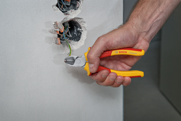 บุคคลนี้ใช้คีมตัดสายไฟหุ้มฉนวนตัดสายไฟจากเต้ารับติดผนัง