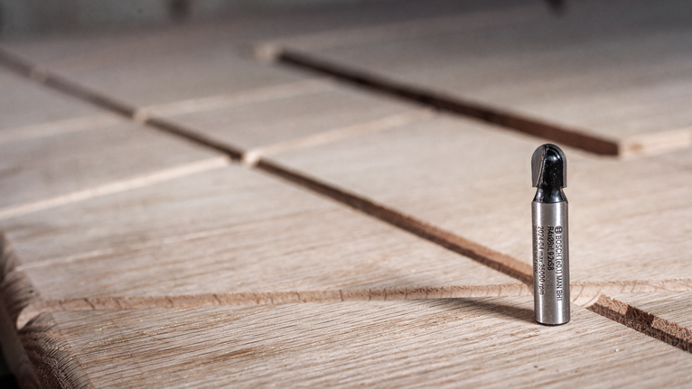 ดอกกัดโลหะตั้งตรงบนพื้นผิวไม้ที่มีร่อง.