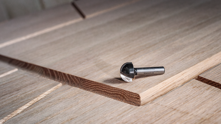 ดอกกัดคาร์ไบด์วางอยู่บนแผงไม้หลายชั้นพร้อมร่องที่ตัดใหม่.