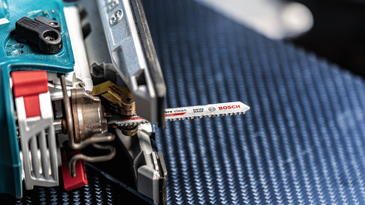 จิ๊กซอว์ที่มีใบเลื่อยโลหะวางอยู่บนพื้นผิวสีน้ำเงินที่มีลวดลาย.