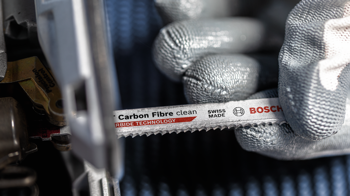 บุคคลที่สวมอุปกรณ์ด้านความปลอดภัยติดตั้งใบเลื่อยคาร์บอนไฟเบอร์เข้ากับเครื่องมือไฟฟ้า.