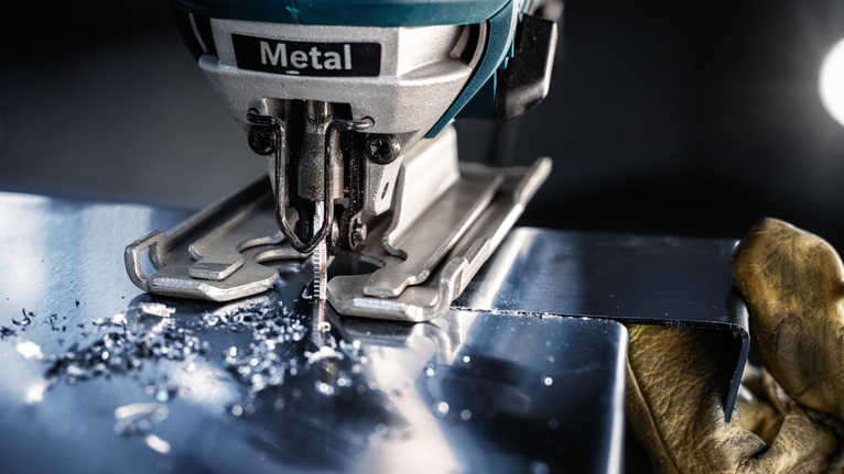 บุคคลที่สวมอุปกรณ์ความปลอดภัยใช้จิ๊กซอว์ตัดแผ่นโลหะ.